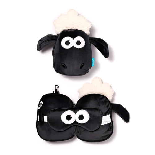 Overhead view of a black Shaun the Sheep themed travel pillow and eye mask set. The top item shows the pillow folded into a plush sheep's head with white wool, while the bottom item displays the unfolded pillow with the black eye mask featuring Shaun's eyes, against a white background.