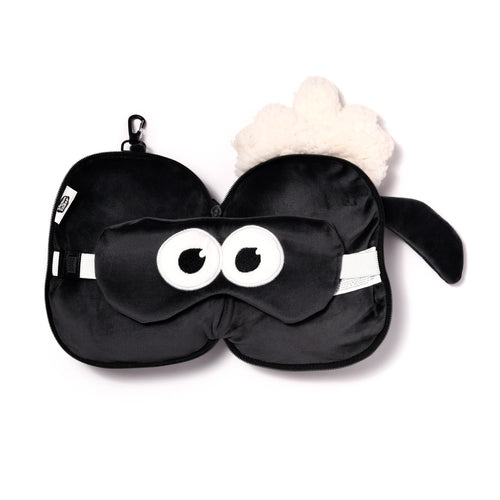 Overhead view of a black Shaun the Sheep travel pillow and eye mask set, featuring a folded velvety pillow with fluffy white wool and a matching eye mask with cartoon eyes.