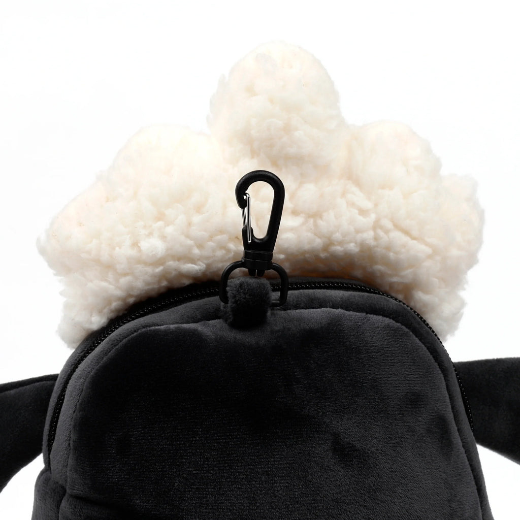 Close-up view of the Shaun the Sheep travel pillow and eye mask set, highlighting the cream fluffy wool, dark grey plush fabric, and black carabiner clip.