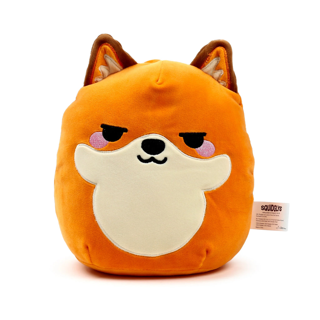 Front view of an orange fox plush toy with a soft, rounded shape. It features a cream muzzle, embroidered sleepy black eyes, a black nose, a subtle smile, and pink blush cheeks. The toy has brown-tipped ears with cream inner details. A white product tag displaying 'SQUIDGLYS' is visible on the right side.