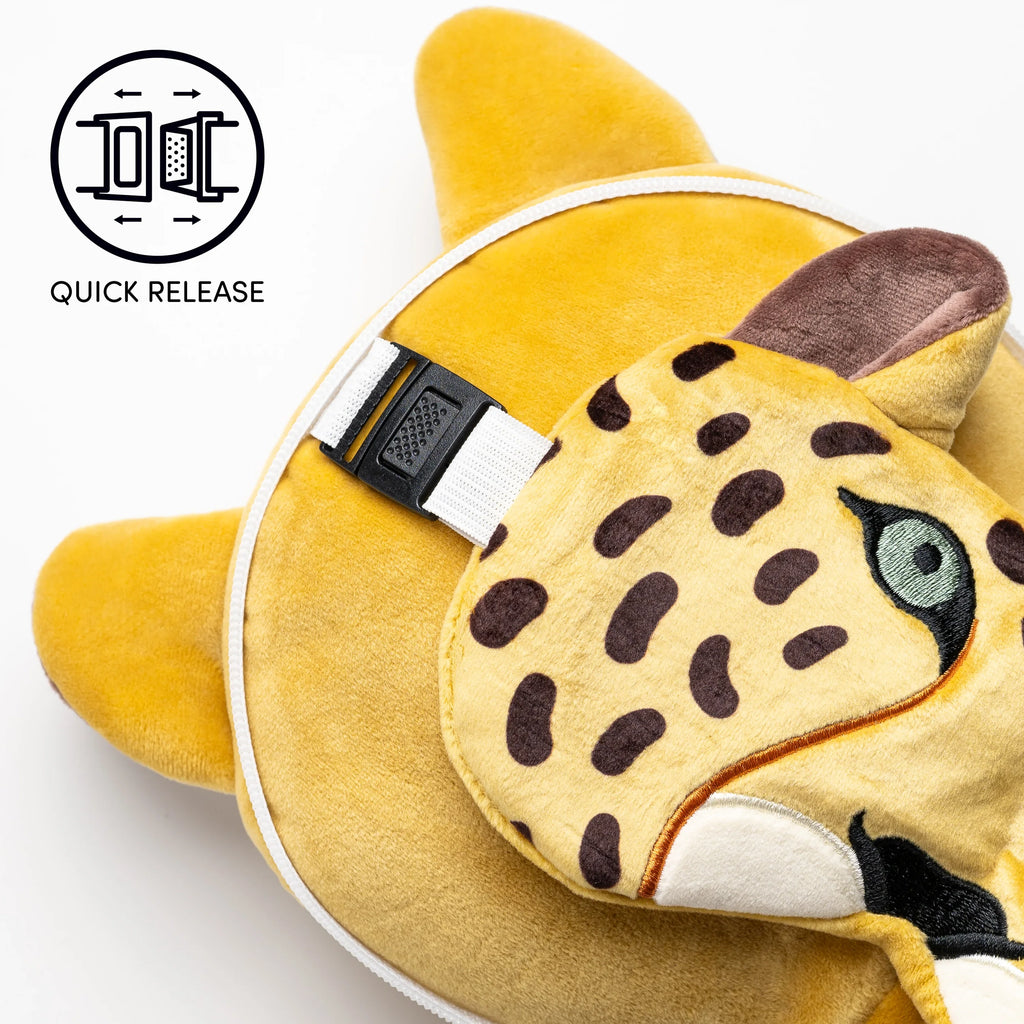 Close-up view of a leopard print travel eye mask with a quick-release strap, resting on a gold-coloured travel pillow.