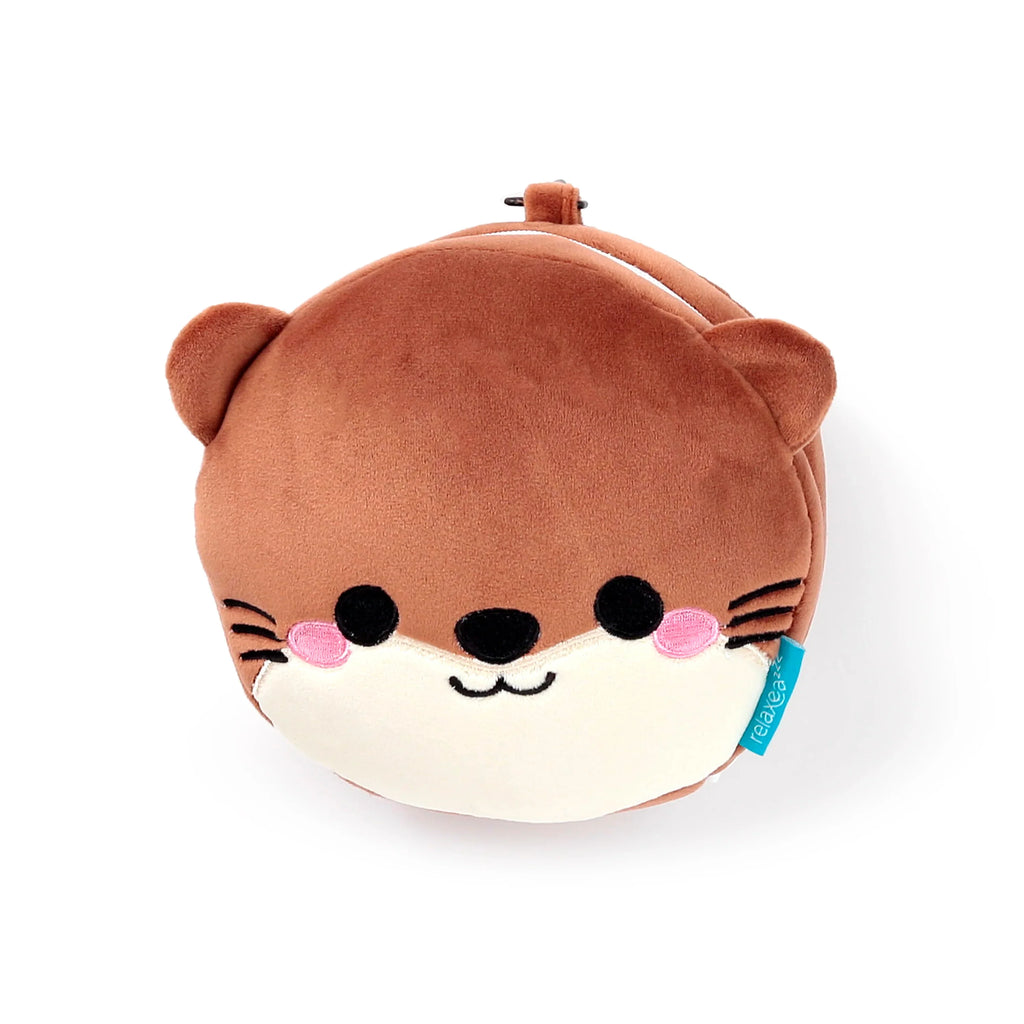 Front view of Henry the Otter travel pillow and eye mask, presented as a brown plush otter character. It features embroidered black eyes, nose, mouth, pink cheeks, and whiskers on a cream-coloured face, with a blue fabric tag on the right.