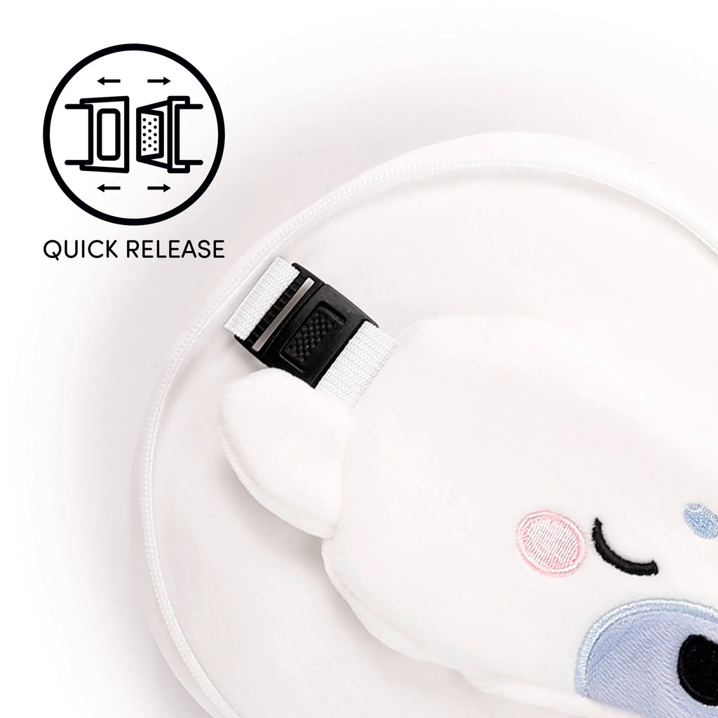 Close-up of the white plush Kai the Seal travel pillow, highlighting its embroidered black eyes, pink cheeks, blue snout, and a black quick-release buckle on a white strap, with a 'QUICK RELEASE' icon.