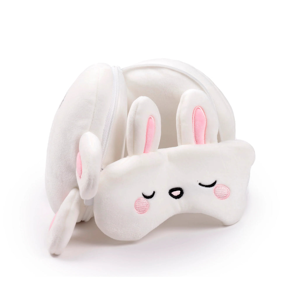 Angled view of a white rabbit travel pillow and eye mask set, featuring a folded pillow with ears and an eye mask with embroidered face details.