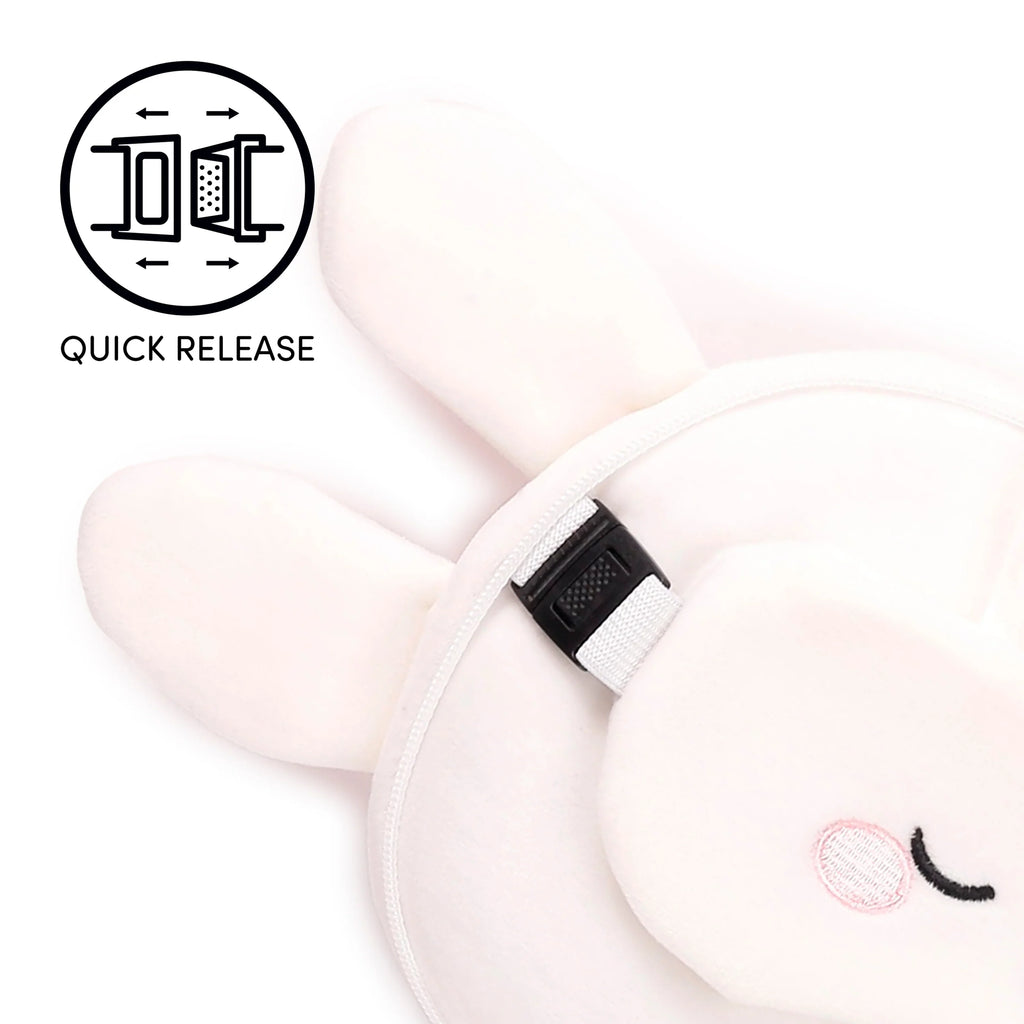 Close-up of a white plush rabbit travel pillow and eye mask, featuring an embroidered pink cheek, sleepy black eye, and a visible black quick-release buckle with its corresponding icon.