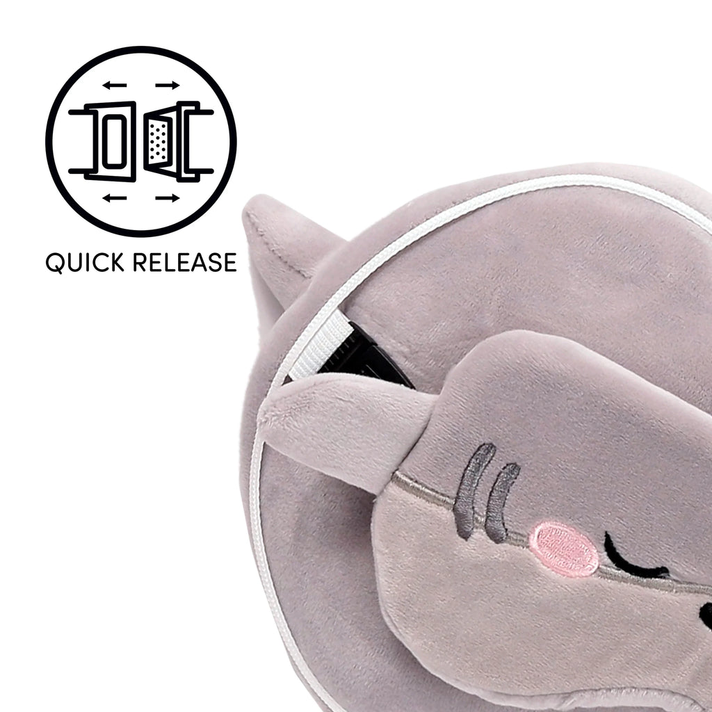 Close-up, angled view of a grey plush Archie the Shark travel pillow and eye mask set. The eye mask features embroidered closed eyes and a pink embroidered cheek detail. A white strap with a black quick-release buckle is visible, connecting parts of the grey U-shaped pillow.