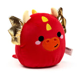 Front view of a round red dragon plush toy with shiny gold wings, small cream horns, yellow head markings, and an embroidered face featuring black eyes, pink cheeks, and an orange snout with a smile, against a white background.