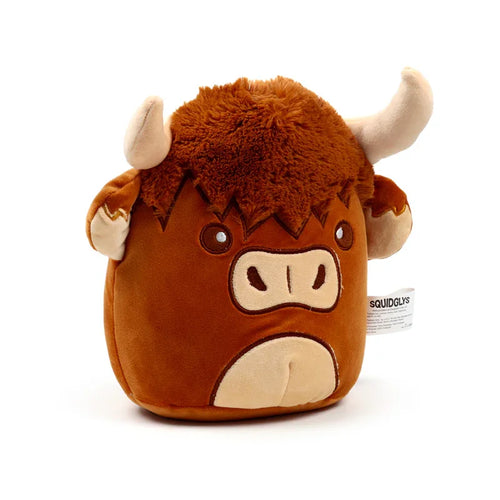 Front view of a brown Squidglys Highland Coo cow plush toy, with shaggy brown fur on its head, light brown horns, embroidered eyes, and snout. A white fabric tag with 'SQUIDGLYS' text is visible on its right side.