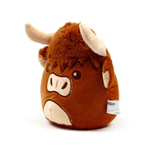 Angled view of a brown plush toy Highland Coo cow, featuring shaggy brown fur, embroidered eyes and snout, with beige horns and inner ears.