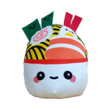 Front view of a white ramen bowl plush toy featuring an embroidered cute face, a yellow noodle-patterned top, and felt toppings, including green nori, a pink-swirled narutomaki, red V-shaped pieces, an orange and white striped ingredient, and a small white and yellow egg character.