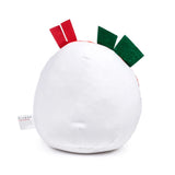 Angled view of a soft white plush toy, featuring red and green felt pieces on top and a white fabric care label on its side.