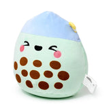Angled view of a green and blue matcha bubble tea plush toy. It features embroidered brown boba pearls, a light blue domed top with a yellow straw, and a winking face with pink blush.