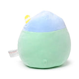 Angled view of a soft, light green and blue matcha bubble tea plush toy with a yellow and white striped straw, and a visible fabric tag on its left side.