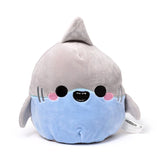 Front view of a grey and light blue plush shark toy with a dorsal fin, embroidered black eyes, pink cheek details, and a smiling mouth showing small teeth, on a white background.