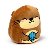 Front view of a brown otter plush toy with a smiling face and embroidered features, holding a blue shell.