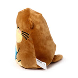 Angled view of a brown Squidglys plush otter toy with a light beige face, pink blush, black whiskers, and a blue embroidered detail on a white background.