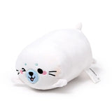 Angled view of a white fluffy Squidglys Kai the Seal Adoramals plush toy, featuring embroidered black eyes, pink cheeks, and a light blue nose.