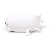 White Kai the Seal plush toy, lying on its side, featuring an elongated body, embroidered eyes, light blue nose, whiskers, and small flippers. A product label is visible on its underside.