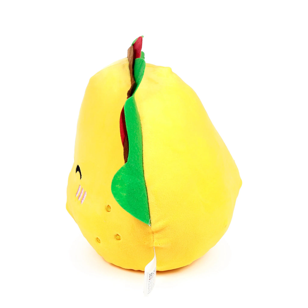 Angled view of a yellow plush taco toy, showing its green, brown, and red filling, with embroidered eyes and pink blush on one side.