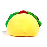 Rear view of a yellow plush taco toy with green, red, and brown fillings, showing the care label.