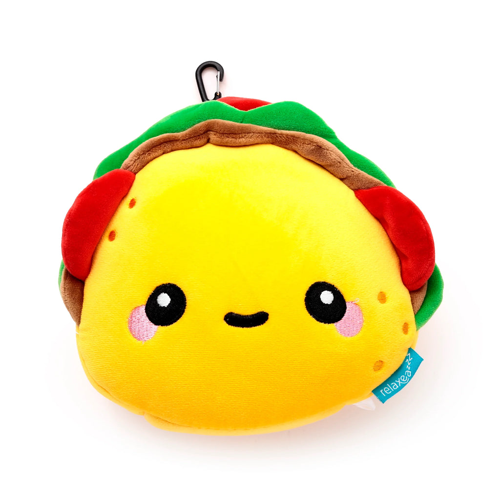 Front view of a yellow plush taco travel pillow with a smiling face, green and brown trim, red details, and a black carabiner clip.