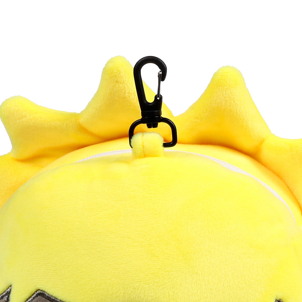 Close-up overhead view of the bright yellow plush travel pillow and eye mask set, featuring a spiky top, a black carabiner clip, and a white zip.
