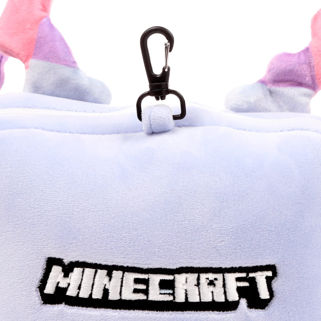 Close-up of a light blue plush Minecraft Axolotl travel pillow, showing the embroidered 'MINECRAFT' logo, a black carabiner clip attached to the top, and pink and purple gill details.