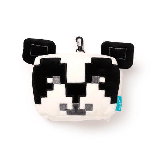 Front view of a plush black and white pixelated panda travel pillow and eye mask, featuring black ears, blocky facial details including eye patches, nose, and mouth, a black carabiner clip, and a light blue fabric tag on the right.