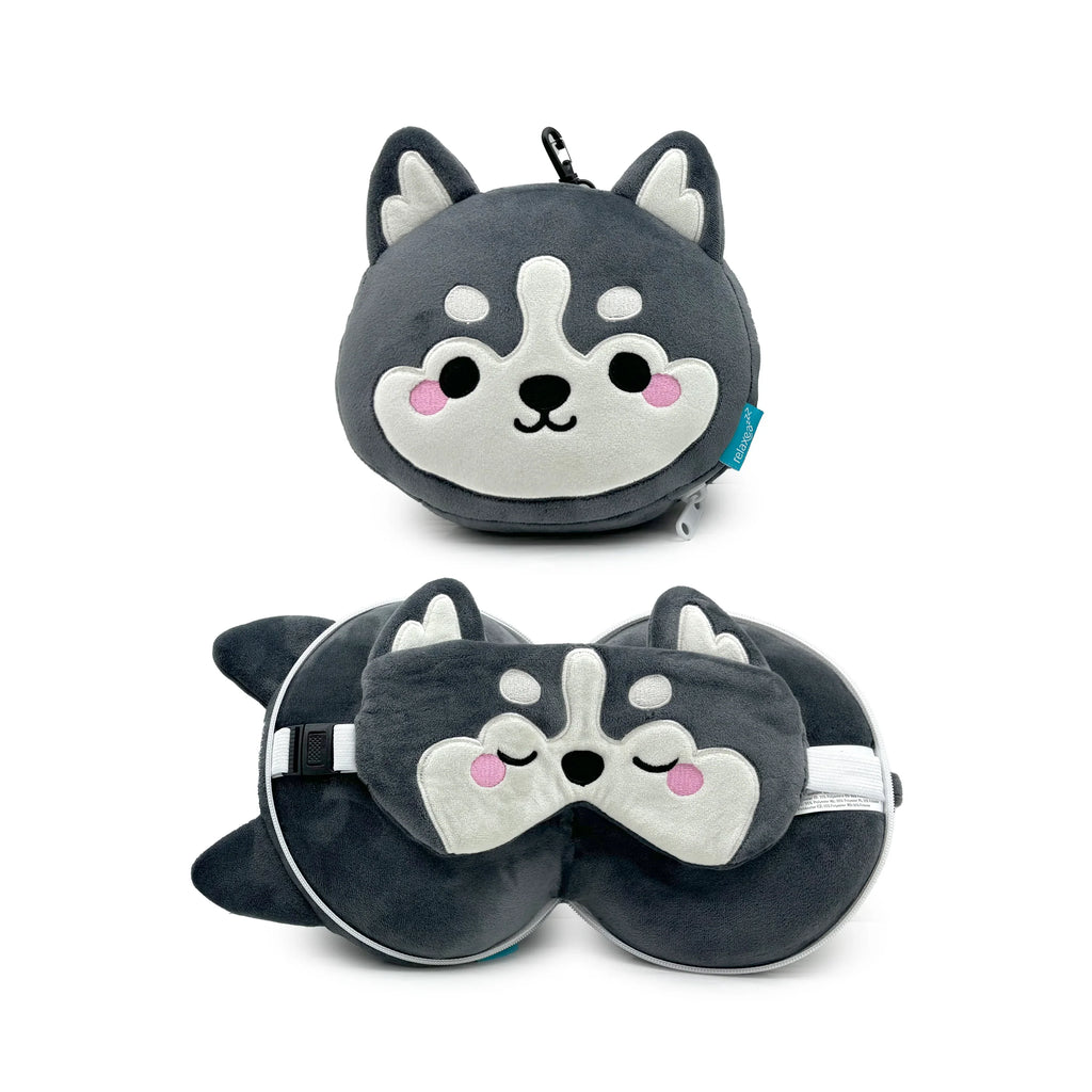 Grey and white plush husky travel pillow and eye mask set, shown both compressed as a husky pouch with a carabiner clip (front view), and unfolded as a U-shaped pillow with a matching sleeping husky eye mask resting on top (angled view).