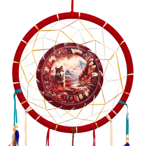Front view of a red dreamcatcher featuring a central autumnal wolf and mountain scene, bordered by feather-like patterns, with gold and white webbing, and dangling blue and natural coloured feathers with beads.