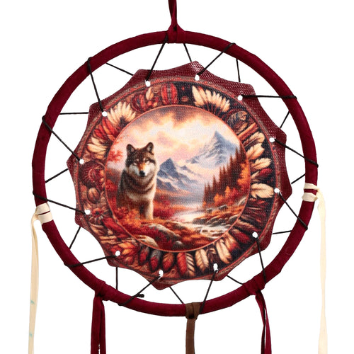 Front view of an autumnal wolf dreamcatcher, featuring a maroon-coloured hoop and a central fabric disc depicting a wolf in a mountainous, autumnal landscape, with maroon and cream ribbons hanging.