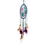 Front view of a dark blue dreamcatcher featuring a central unicorn illustration on a blue and green background, with hanging cream, teal, and dark blue ribbons, wooden and purple beads, and brown, beige, and dark purple feathers.
