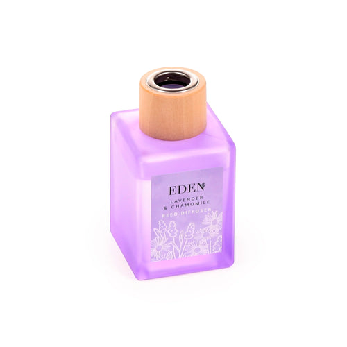 Angled view of a frosted lavender reed diffuser in a square bottle, with a natural wood stopper and a label featuring white lavender and chamomile floral illustrations.