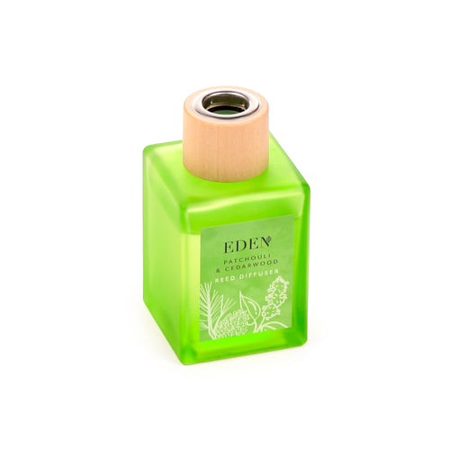 Angled view of a square bright green glass reed diffuser with a light wooden cap. The label displays 'Patchouli & Cedarwood' and white botanical illustrations.