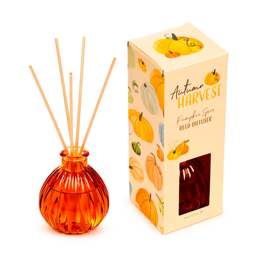 Angled view of an Autumn Harvest Pumpkin reed diffuser, showcasing an orange, ribbed glass bottle containing natural reeds. Next to it, the beige display box is visible, featuring 'Autumn Harvest Pumpkin Spice Reed Diffuser' text on its front and an array of pumpkin illustrations on its visible sides.