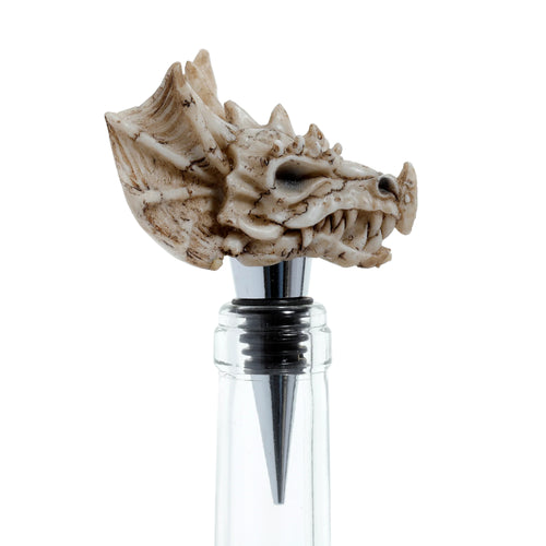 Detailed bone-coloured dragon skull bottle stopper, showing its jagged teeth and textured head, fitted into a clear glass bottle neck.