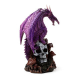 Angled view of a purple dragon figurine with textured wings, perched on a grey skull; the base features brown mushrooms and moss.