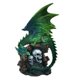 Emerald green winged dragon figurine with textured wings, perched on a dark base featuring two grey skulls, brown mushrooms, and a smaller green dragon.