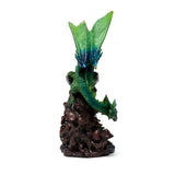 Emerald green and blue dragon figurine, photographed from an angled perspective, showcasing its large translucent wings and scaled back. The dragon is perched on a dark brown, root-like base with mushrooms.