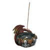 Dark Legends dragon incense burner, featuring a red and gold coloured dragon with blue eyes perched on a dark, rocky base. The base is decorated with a ring of orange and yellow flames surrounding white skulls and skeletons. A brown incense stick is inserted upright in the centre.