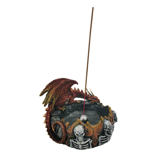 Dark Legends dragon incense burner, featuring a red and gold coloured dragon with blue eyes perched on a dark, rocky base. The base is decorated with a ring of orange and yellow flames surrounding white skulls and skeletons. A brown incense stick is inserted upright in the centre.