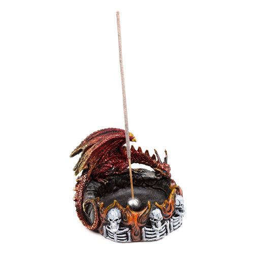 Angled view of a red and gold dragon incense burner, showing a coiled dragon with textured scales and wings, on a base decorated with orange flames and white skulls. A single incense stick is inserted in the holder.