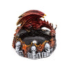 Angled view of a dark fantasy incense burner, featuring a red and gold dragon with textured wings perched above a ring of orange and black flames, with white skulls and skeleton ribs around the base and a dark central well.