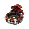 Angled view of a sculpted dragon incense burner, featuring a red and gold dragon with outstretched wings on a black rocky base. The base is decorated with orange flames and multiple white skeletal figures, with a central silver incense holder.