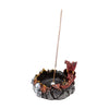 Angled view of a dark fantasy incense burner, depicting a red and gold dragon with blue eyes emerging from a dark, rocky base with embedded skulls, an incense stick standing upright in the central ash holder.