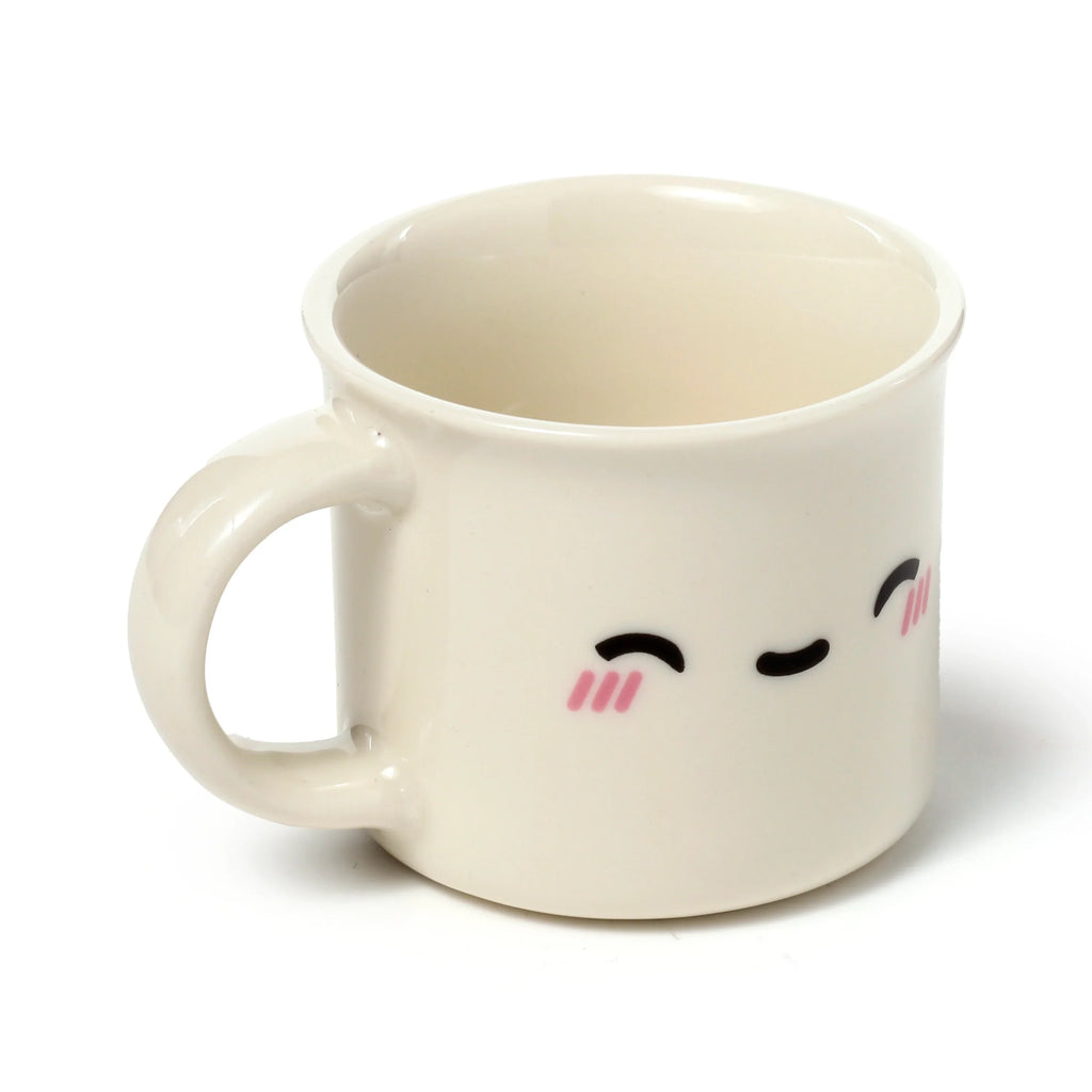 Front 3/4 view of a single cream porcelain espresso cup featuring a cute character face design with black eyes and pink blush, on a white background.