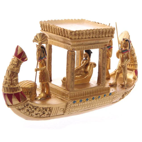 Front-side view of a decorative gold Egyptian canopy boat figurine with a reclining figure under a canopy and standing figures.