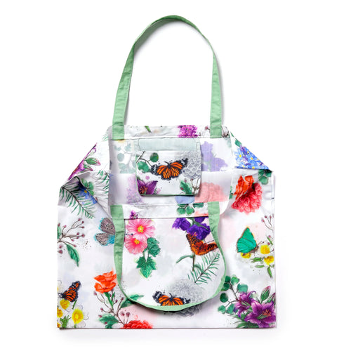 Front view of a white foldable shopping bag with green handles, featuring a colorful butterfly and floral meadow pattern.