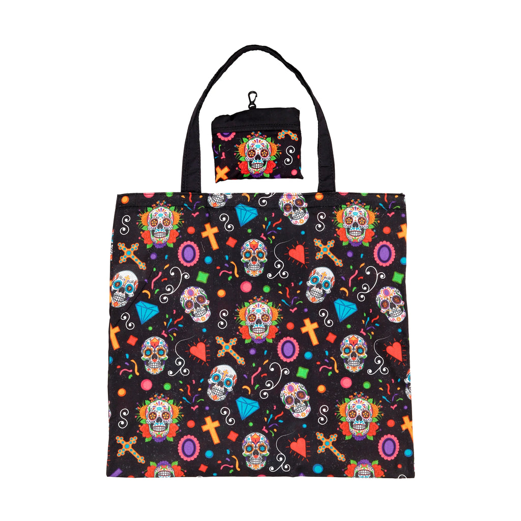Front view of a black foldable shopping tote bag, featuring a vibrant Day of the Dead pattern with sugar skulls, flowers, crosses, hearts, diamonds, and confetti. A matching small pouch with a carabiner clip is visible above.
