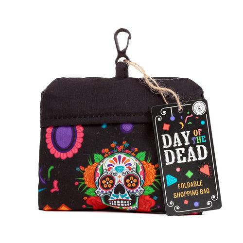 Front view of a black foldable RPET shopping bag, featuring a colourful Day of the Dead sugar skull design with vibrant flowers. A black carabiner clip is attached, with a product tag hanging from twine.